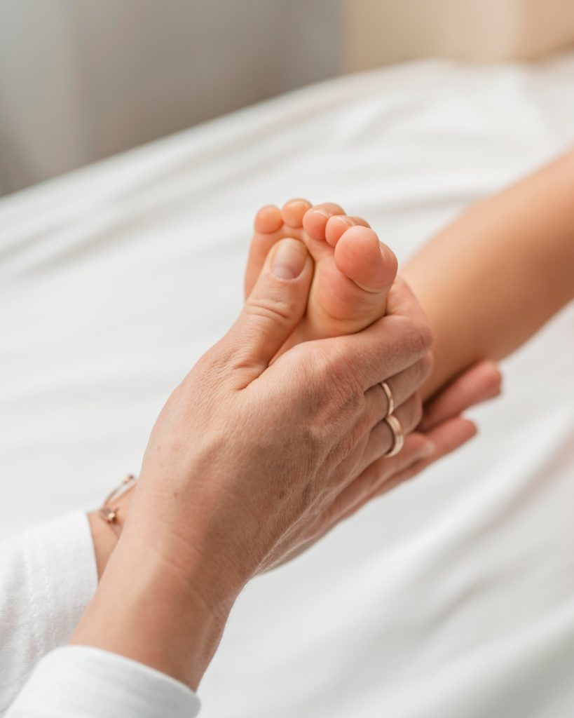 Hand behandelt Fuß eines Babys osteopathisch